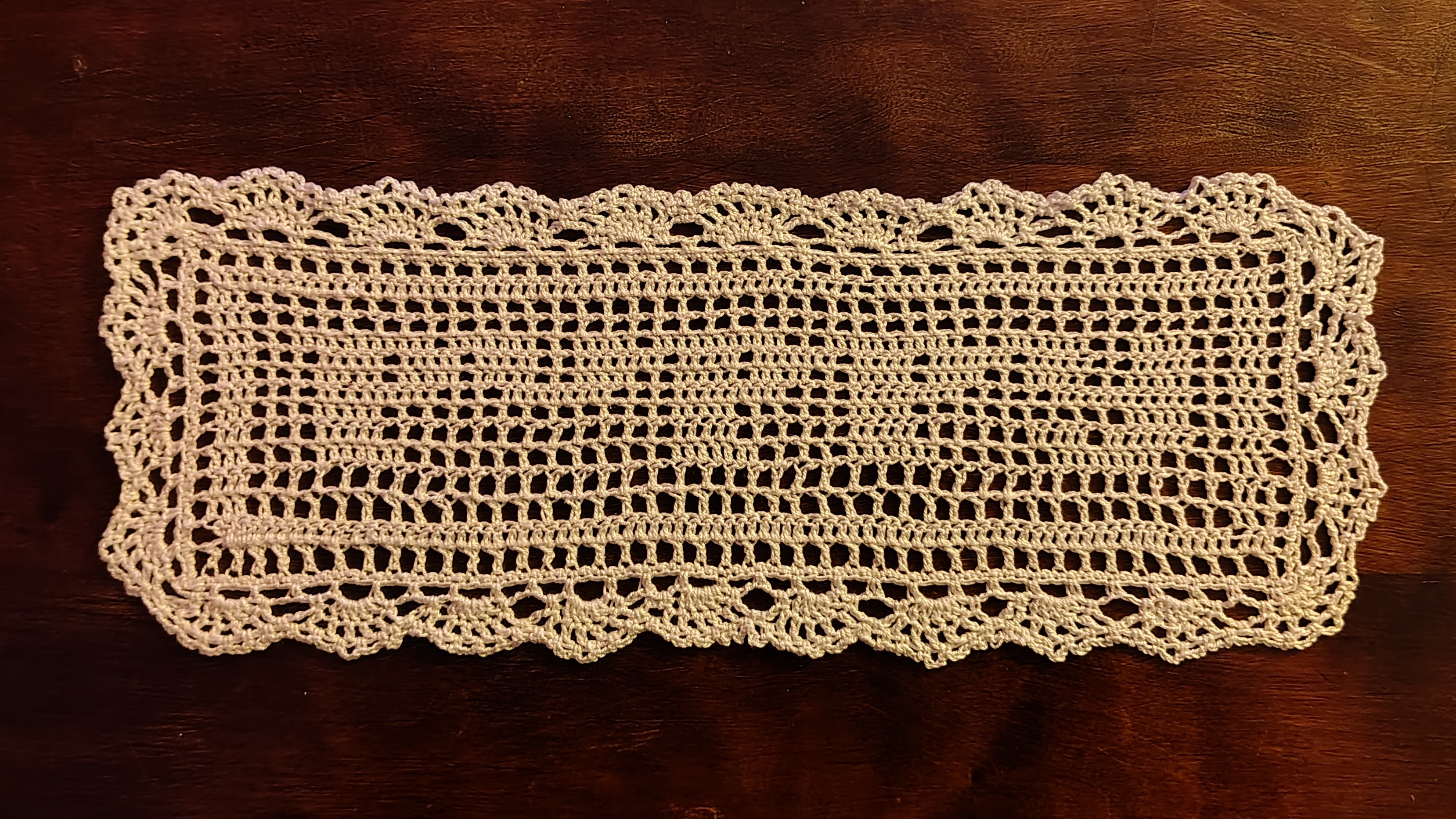a filet crochet doily with a design that says 'puppy' in a lowercase cursive font